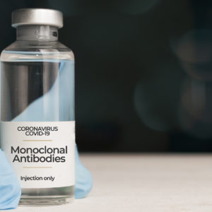 Doctor hold a vial of monoclonal antibodies , a new treatment for coronavirus Covid-19, on a white table vial of monoclonal antibodies