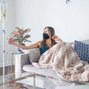 Monoclonal Antibody IV Therapy woman getting an IV therapy on her couch