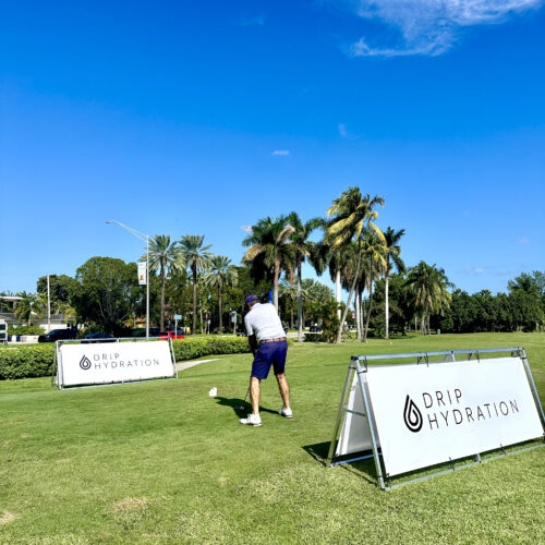 LARGE-SCALE man playing golf, drip hydration's logo in the back