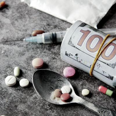 drug-addiction cash, syringe and a spoon with tablets and pills on a table