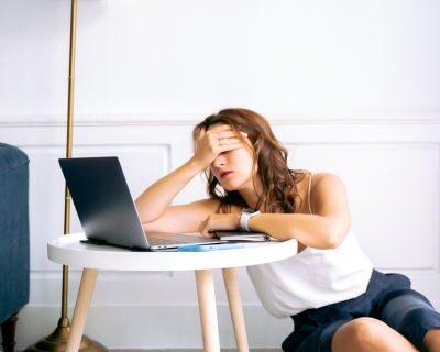 tired woman holding her head looking at her laptop tired woman holding her head looking at her laptop