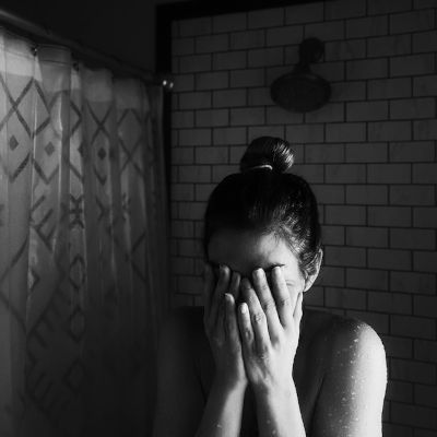 panic-attack A woman covering her face in front of a shower